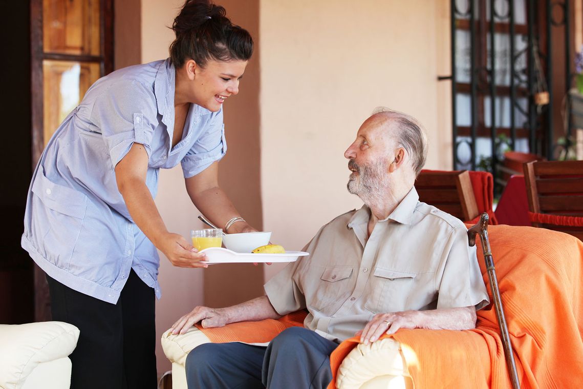 A home care nurse bring a patient his meal